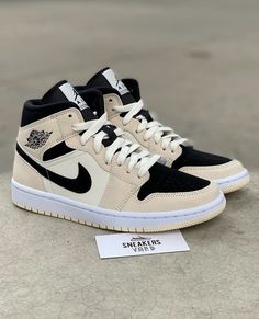 a pair of black and white sneakers sitting on top of a cement floor next to a sign