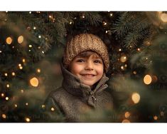 a young boy wearing a knitted hat and jacket in front of a christmas tree