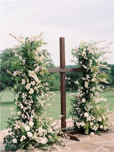 the cross is surrounded by white flowers and greenery