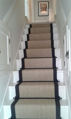 a set of stairs leading up to a hallway with carpet on the bottom and black trim