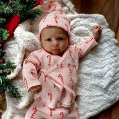 a baby laying on top of a blanket next to a christmas tree