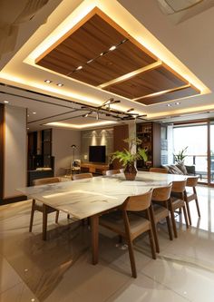 a large dining room table with chairs and a plant in the center is illuminated by recessed lighting