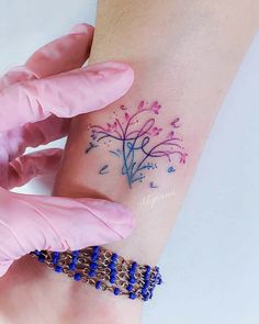 a woman's arm with a tattoo on it and a blue beaded bracelet