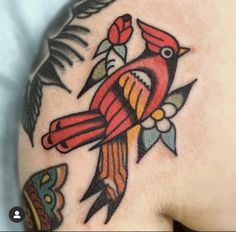 a colorful bird tattoo on the back of a man's shoulder and arm,