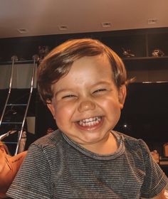 a young boy smiling and holding a piece of pizza