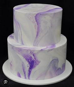 a three tiered cake with purple and white marbled icing on it's sides