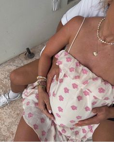 a pregnant woman sitting on the floor with her belly wrapped up in a pink flowered dress