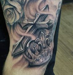 a man with a cross and crown tattoo on his arm is shown in black and grey