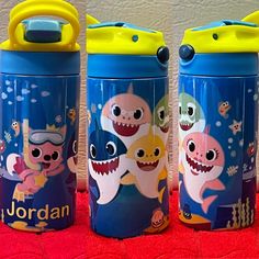 three children's water bottles with cartoon images on them, one blue and the other yellow