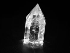 a clear crystal on a black surface with light coming from it's center point