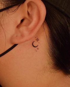 a woman's ear has a small star and moon tattoo on it