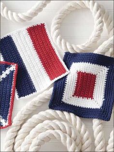 two crocheted squares are next to rope on a white surface with red, white and blue colors