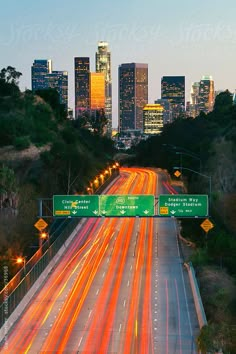 the city skyline is lit up at night by an overpass with cars driving on it