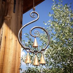 an old fashioned wind chime hanging from a wooden structure with trees in the background