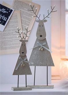 two wooden reindeer statues with bows on their heads and antlers in front of an open book