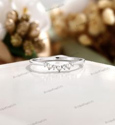 a white gold ring with three diamonds on it, sitting on top of a table