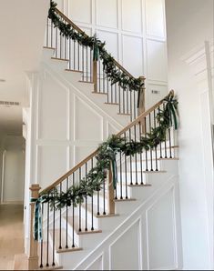 the stairs are decorated with greenery and ribbon for christmas time, while the banister is