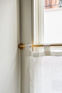 the curtain is hanging in front of an open window with white linens on it