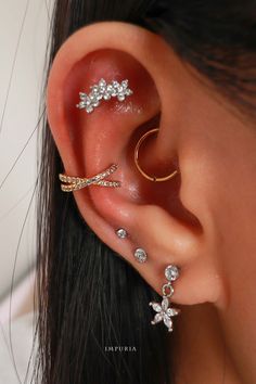 a woman wearing three different types of ear piercings