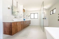 a large bathroom with white walls and wooden cabinets, along with a walk in shower