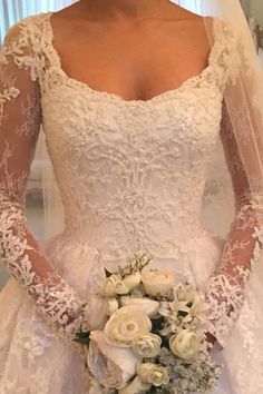 a woman in a wedding dress holding a bridal bouquet with white flowers on it