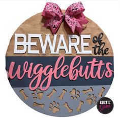 a wooden sign that says beware of the wriglebuts and has a pink bow on it