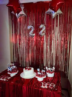 the table is covered with red foil streamers and white frosted cake for two