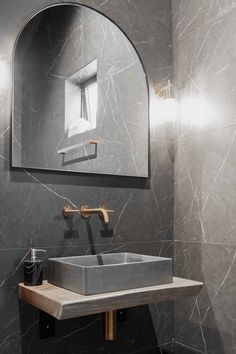 a bathroom sink sitting under a mirror in front of a wall mounted faucet