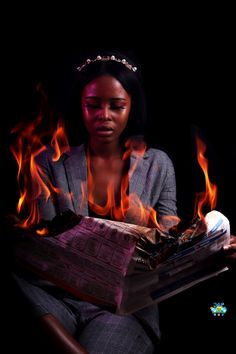 a woman sitting in front of a book on fire