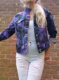 a woman wearing white jeans and a blue jacket standing in front of a brick wall