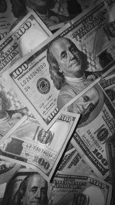 many hundred dollar bills spread out on top of each other in black and white photo