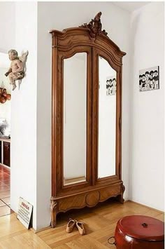 a wooden armoire sitting on top of a hard wood floor next to a white wall