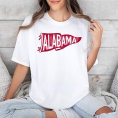 *Also available as a sweater. See below.* This Alabama Pennant T-Shirt is perfect for showing off your love for the Crimson Tide! Featuring a vibrant pennant flag design, this t-shirt is made of soft and comfortable fabric. Show your team pride in style with this unique and playful t-shirt. Pre-shrunk White Sports Fan T-shirt, White Pre-shrunk Sports Fan T-shirt, Sports Fan White T-shirt For Fan Merchandise, White Pre-shrunk T-shirt For Sports Fans, White T-shirt For Sports Fans, White Screen Print T-shirt For Game Day, White T-shirt For Team Spirit Fan Gear, White T-shirt For Fan Gear With Team Spirit, White T-shirt With Screen Print For Sports Fans