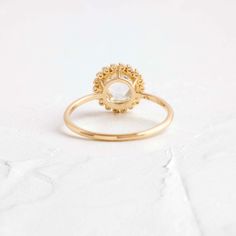 a gold ring with a white diamond in the center on a white background, close up