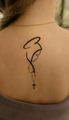 the back of a woman's neck with a tattoo on her shoulder and cross