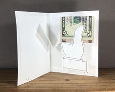 an open card with a cutout of a hand holding a dollar bill in front of it