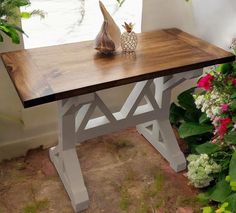 a wooden table with two vases on top of it next to flowers and plants