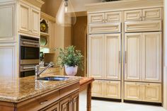 a kitchen with marble counter tops and wooden cabinets, along with a large center island