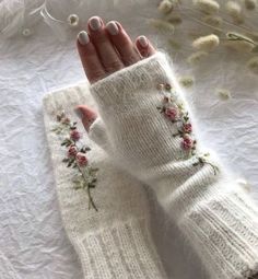 a woman's hand wearing white gloves with flowers on them