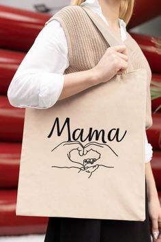 a woman carrying a tote bag with the word mama printed on it