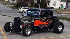 an orange and black car with flames on it's hood parked in a parking lot