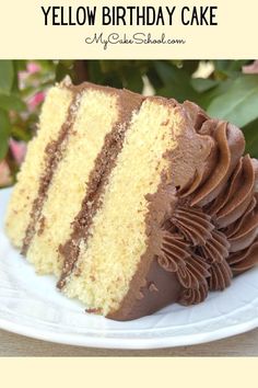 a slice of yellow birthday cake with chocolate frosting on a white plate next to flowers