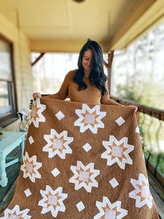 a woman holding up a brown and white quilt