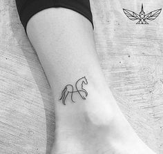 a black and white photo of a small horse tattoo on the left ankle, with an arrow in the middle