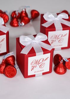 four red boxes with white bows and hearts on them, one has a monogrammed ribbon