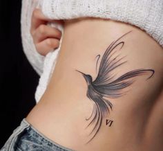 a woman's stomach with a bird tattoo on her side and the word vi written in cursive writing