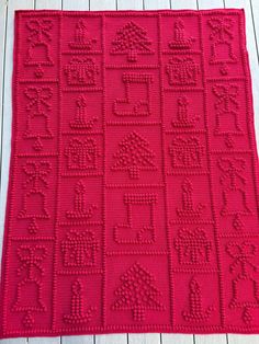 a red crocheted rug sitting on top of a wooden floor next to a white wall