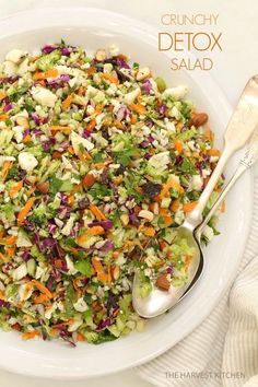 a salad with carrots, celery, lettuce and nuts in a white bowl