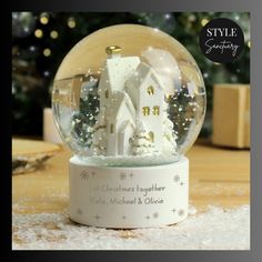 a snow globe with a house in it on a table next to a christmas tree