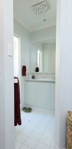 an open door leading to a bathroom with white tile flooring and counter top sinks